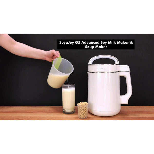 Fresh soy milk being poured from SoyaJoy G5 milk maker into a glass at home