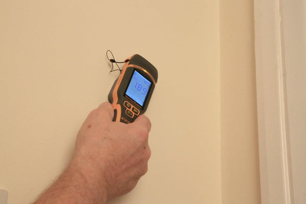 Handheld Protimeter SurveyMaster moisture meter detecting moisture near interior wall corner
